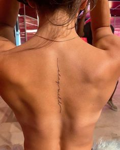 the back of a woman's body with a tattoo on her left shoulder and lower back