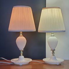 two white lamps sitting on top of a wooden table