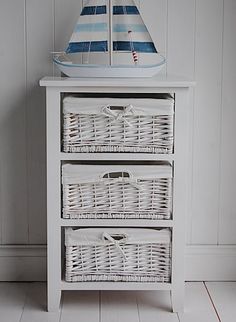 three wicker baskets are stacked on top of a white cabinet in the corner of a room