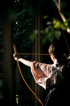 the man is practicing his archery skills in the dark room with no one around him