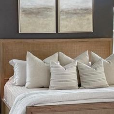 a bed with four pillows on it and two framed pictures above the bedspread