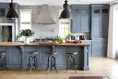 an image of a kitchen setting with blue cabinets and bar stools in the center