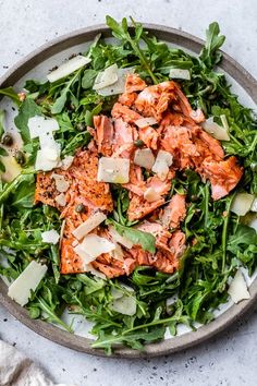 a bowl filled with greens and meat on top of a table