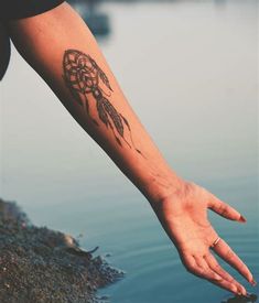 a person's arm with a tattoo on it and a hand reaching out to the water