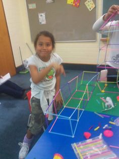 two children are playing with construction toys in the school's playroom while another child looks on