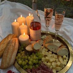 a platter filled with cheese, meat and bread next to two glasses of wine