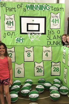 two girls are standing in front of a green wall with basketballs and numbers on it