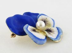 "Vintage 14K yellow gold, enamel and pearl large Pansy Brooch/Pendant by Larter & Sons (New Jersey Manufacturer), c. 1930s-1940s Beautiful very large pansy flower enameled in blue hues The front petals are primarily white with just a light blue border while the back petal enameled in blue entirely The center highlighted with a cultured pearl and painted with realistic markings in brown The back completed by original pin fitting and a folding bail Pansy stamped \"14K\" and maker's mark for La Yellow Gold Enamel Brooches, Elegant Blue Enamel Pin, Elegant Yellow Gold Enamel Brooches, Elegant Blue Enamel Brooches, Yellow Gold Enamel Brooch Jewelry, Unique Yellow Gold Enamel Brooch, Elegant Yellow Gold Enamel Pin Gift, Elegant Enamel Brooch Pin, Yellow Gold Enamel Brooches For Gifts