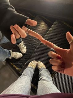 two people standing on an escalator with their hands extended out to touch each other