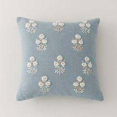 a light blue pillow with white flowers on the front and back, against a gray background