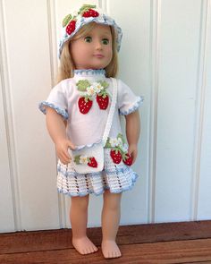 a doll wearing a dress and hat with strawberries on the top, standing in front of a door