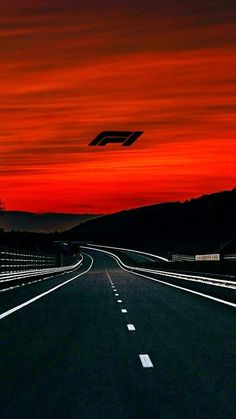 an empty road with the sun setting in the background and a plane flying over it