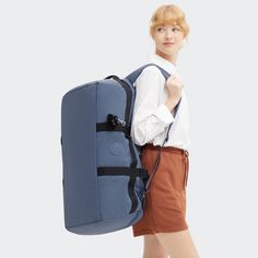 a woman carrying a large blue backpack on her back while standing in front of a white background