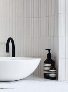 a white sink sitting next to a black faucet on top of a counter