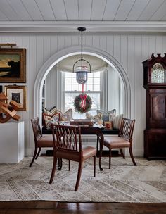 a dining room table with chairs and a clock on the wall in front of it