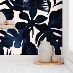 the wallpaper in this kitchen is painted with dark blue leaves and white vases