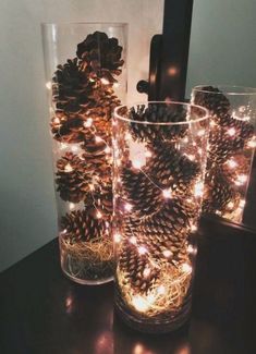 two glasses filled with pine cones sitting on top of a table next to each other