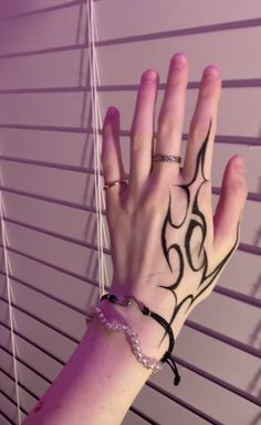 a woman's hand with tattoos on her left arm and wrist, next to blinds