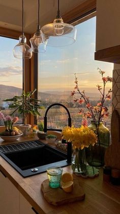 a kitchen with a large window looking out at the mountains and flowers in vases