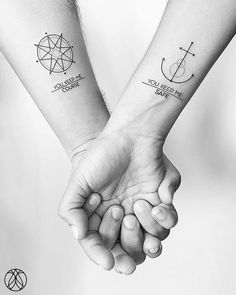 two people holding hands with tattoos on their arms