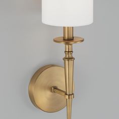 a wall light with a white shade on the top and bottom arm, in an antique brass finish