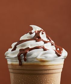 a chocolate drink with whipped cream and drizzled on top is sitting in front of a brown background