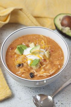 a white bowl filled with soup next to an avocado