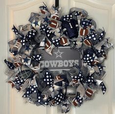 a wreath made out of footballs and bows on a door with the word cowboys painted on it