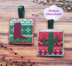 two cross stitch christmas ornaments on a wooden table with text overlay that says pattern downtown