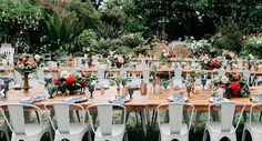 an outdoor table set up with white chairs and floral centerpieces