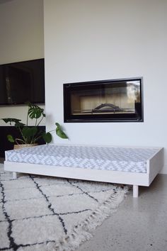 a white bed frame in front of a fireplace