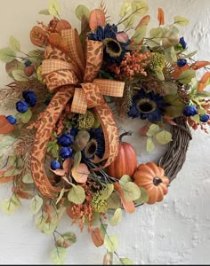 a wreath with blue flowers, orange and green leaves is hanging on the wall next to a door