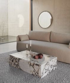 a marble coffee table sitting on top of a carpeted floor next to a couch