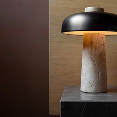 a black and white lamp sitting on top of a marble block next to a wooden wall