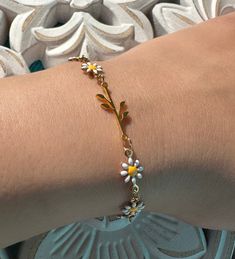 This stunning bracelet features a delicate chain of daisy flowers and a gorgeous golden stainless steel branch with leaves. The combination of the two creates a unique and beautiful design that is perfect for anyone who loves nature-inspired jewelry. The daisy flowers add a touch of playfulness and whimsy to the bracelet, while the golden stainless steel branch and leaves create an elegant look. The bracelet is perfect for any occasion, whether you're dressing up for a special event or adding a touch of elegance to your everyday look. Get your bracelet now and add a touch of nature to your jewelry collection! Measurement: 14cm + 6 inch extender Handmade Gold Bracelets For Spring, Gold Bracelet Jewelry For Spring, Spring Gold Bracelet Jewelry, Gold Spring Bracelet, Spring Gold Jewelry With Flower Charm, Minimalist Gold Jewelry For Spring, Dainty Spring Bracelet Jewelry, Everyday Gold Bracelets For Spring, Spring Dainty Bracelet Jewelry