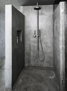 a shower head in the corner of a room with concrete walls and flooring on both sides