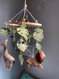 a baby crib with stuffed animals hanging from it's sides and leaves on the ceiling