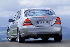 the rear end of a silver mercedes benz cls parked on top of a mountain