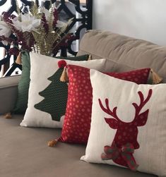 three christmas pillows sitting on top of a couch next to a vase filled with flowers