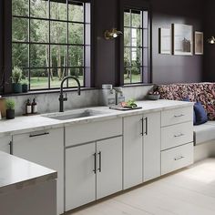 a kitchen with white cabinets and black walls, along with windows that look out onto the yard