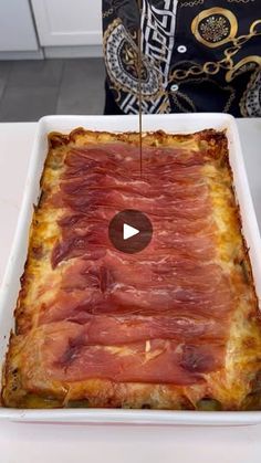 a square white dish filled with meat on top of a table