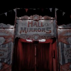 the entrance to an old fashioned theatre with red curtains and banners hanging from it's sides