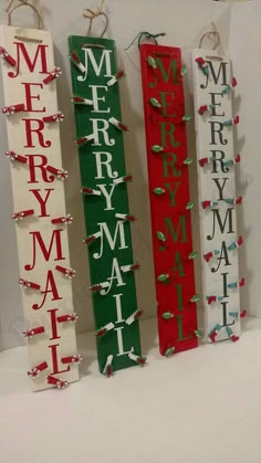 four wooden christmas signs are hanging on a white wall and decorated with red, green, and white ribbons