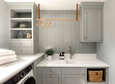 a washer and dryer in a small room with gray painted wood paneling