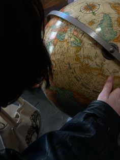 a person holding onto a large globe with writing on it and a pair of scissors