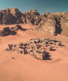 an old village in the desert surrounded by rocky mountains and sand dunes with no people