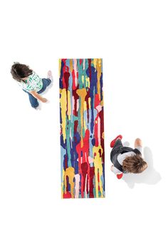 two children are playing in front of a colorful rug