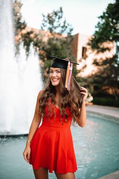 a woman in a graduation cap and gown standing next to a fountain