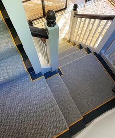 an aerial view of stairs and railings in a building with blue carpeting, white walls and black handrails