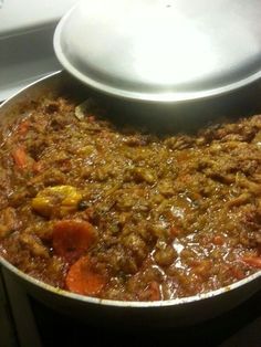 a pot filled with food sitting on top of a stove next to a white plate